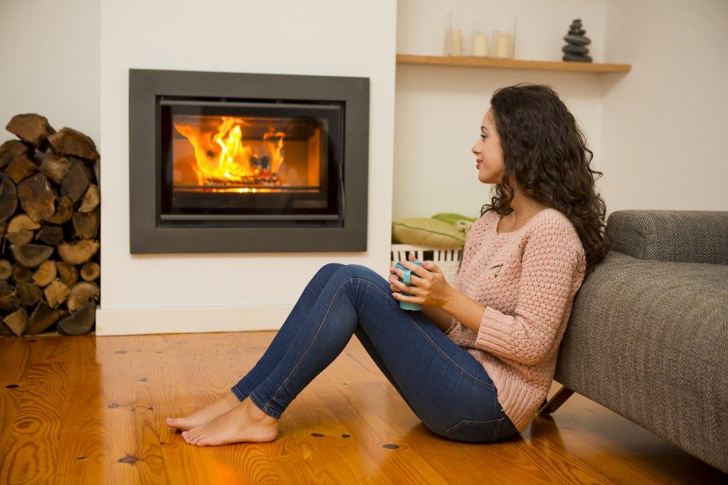 woman drinking coffee in front of fireplace