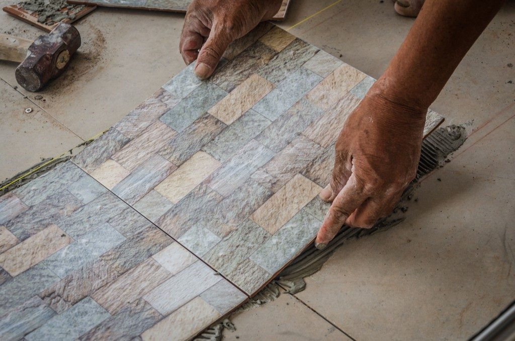 person installing floor tiles