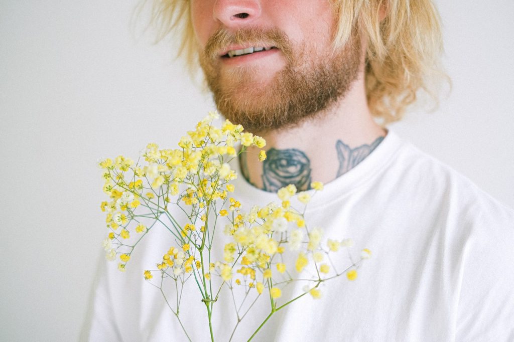 man smiling while holding some flowers