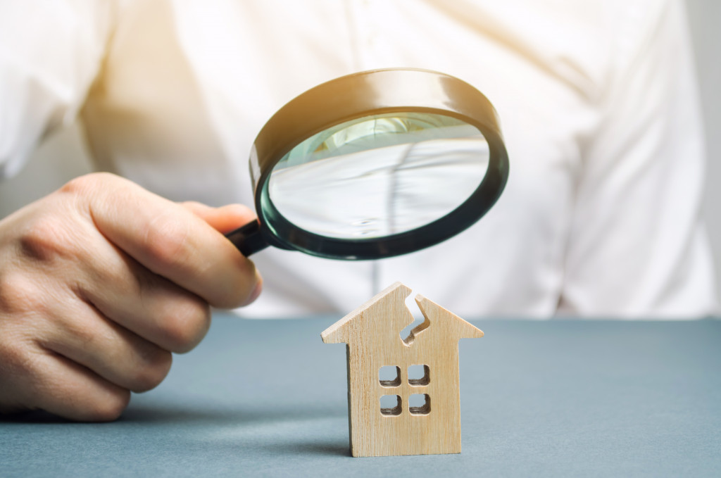 person using a magnifying glass on wood house