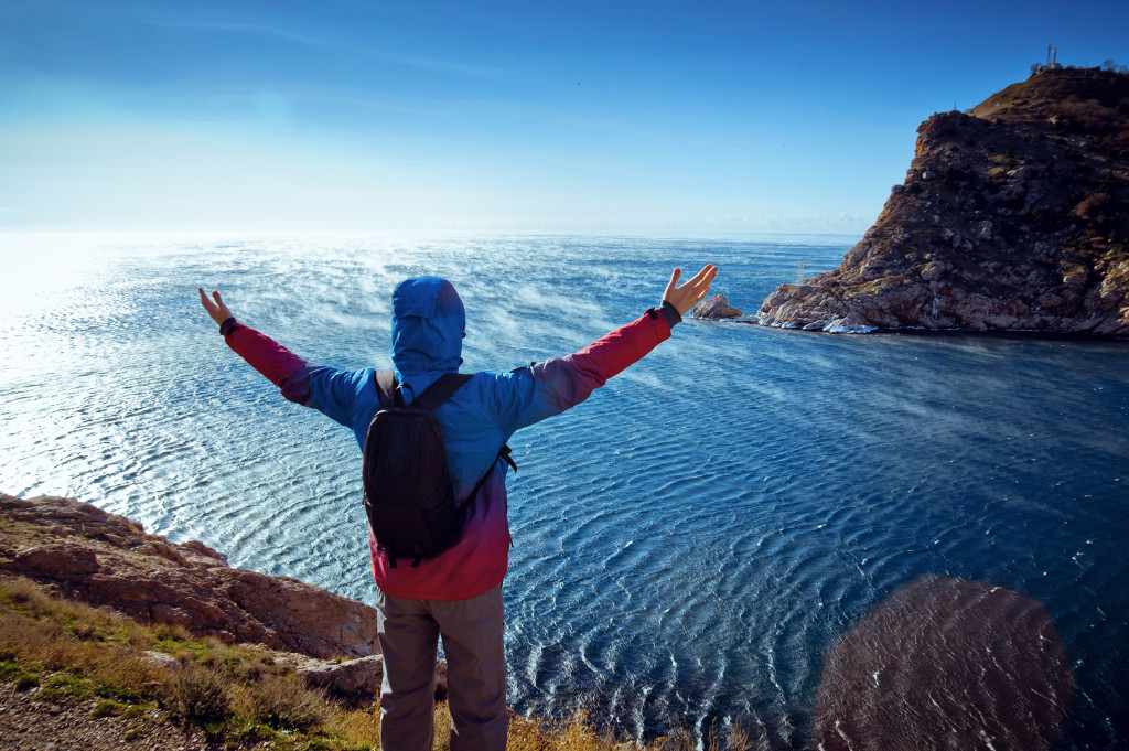 standing on a mountain with his arms raised