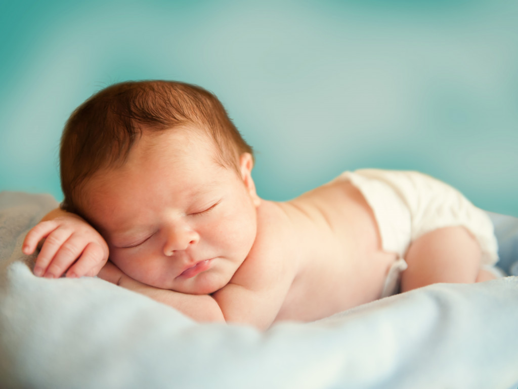 a baby sleeping on a blue sheet