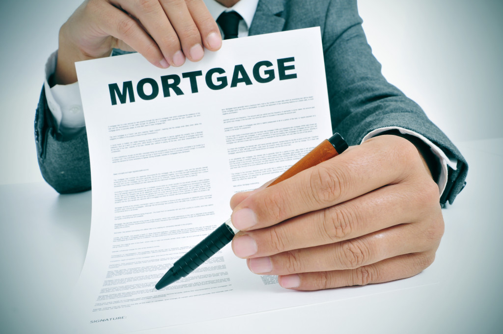 A man in a suit holding a mortgage contract and a pen