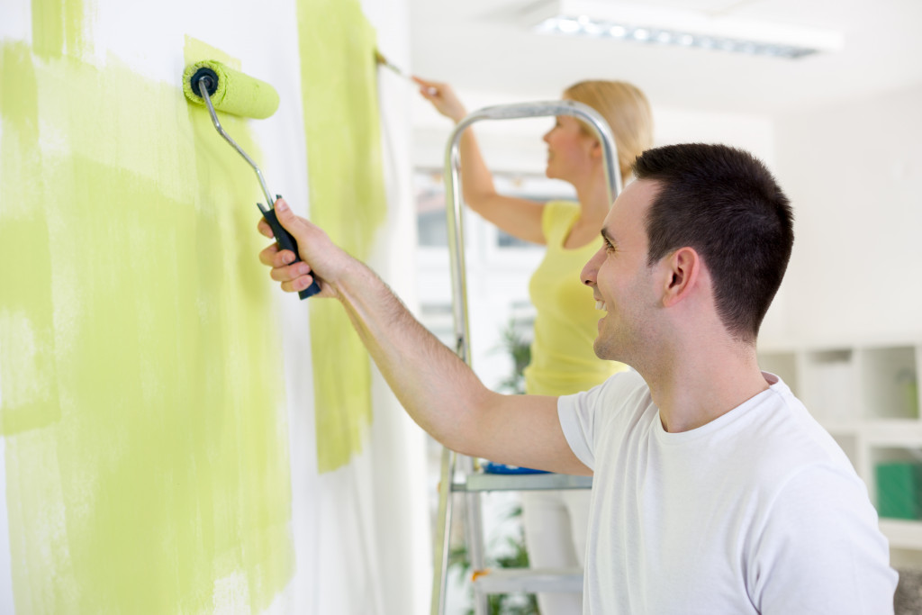 Young couple smiling while painting their home.