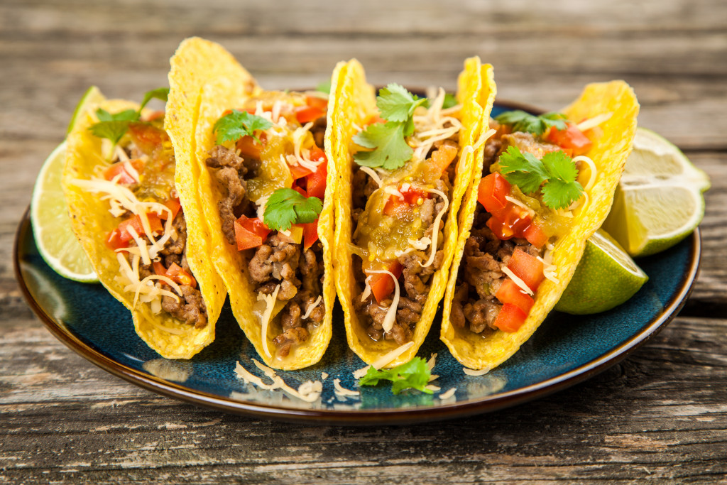 Four tacos on a black plate