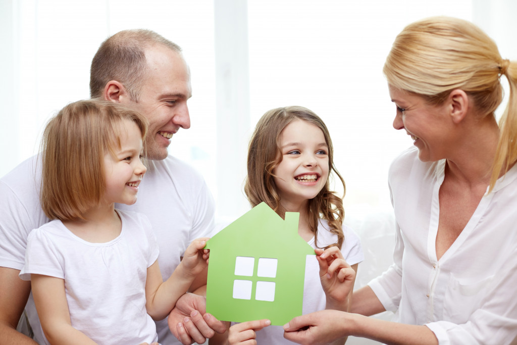 a happy family holding a green model house