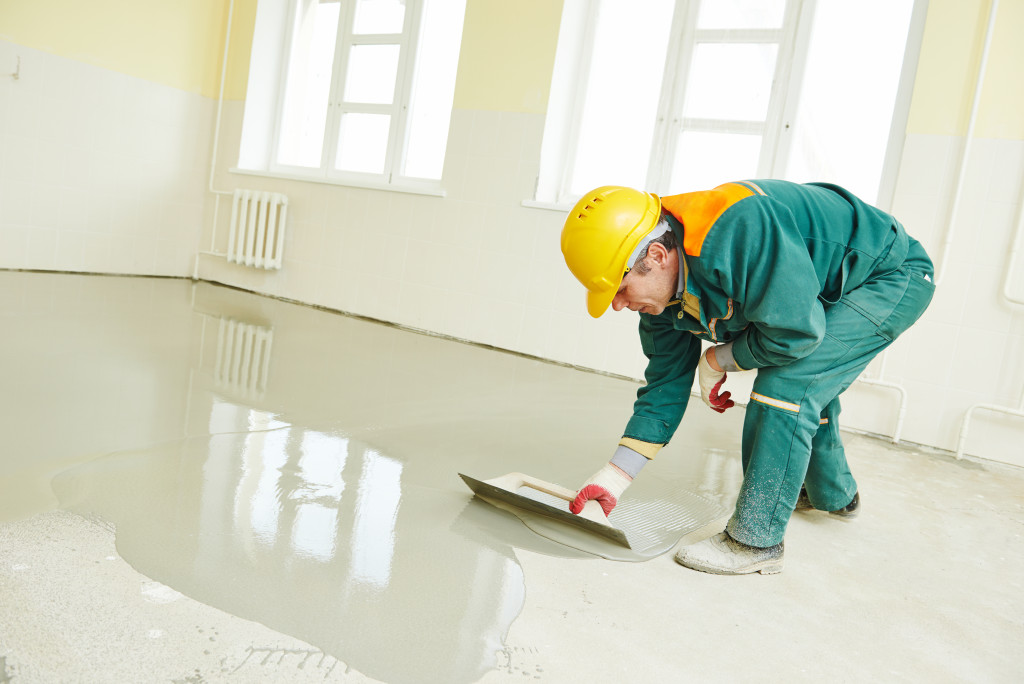 a worker applying cement on the ground and leveling it