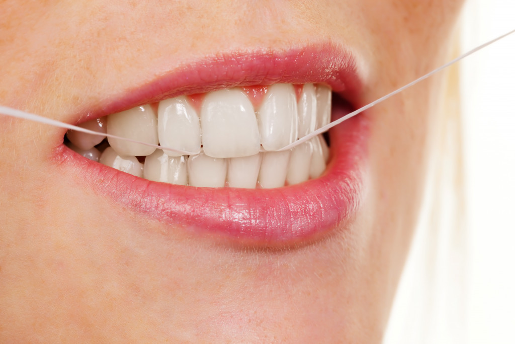 young woman using dental floss to clean teeth