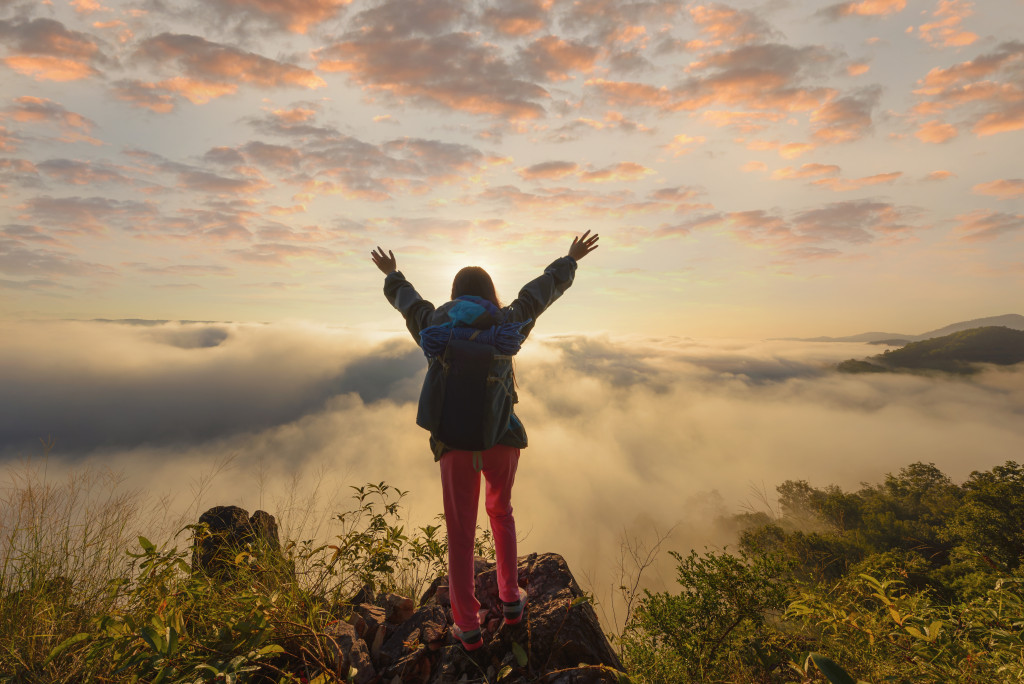 a woman standing on a mountain peak with hands in the air