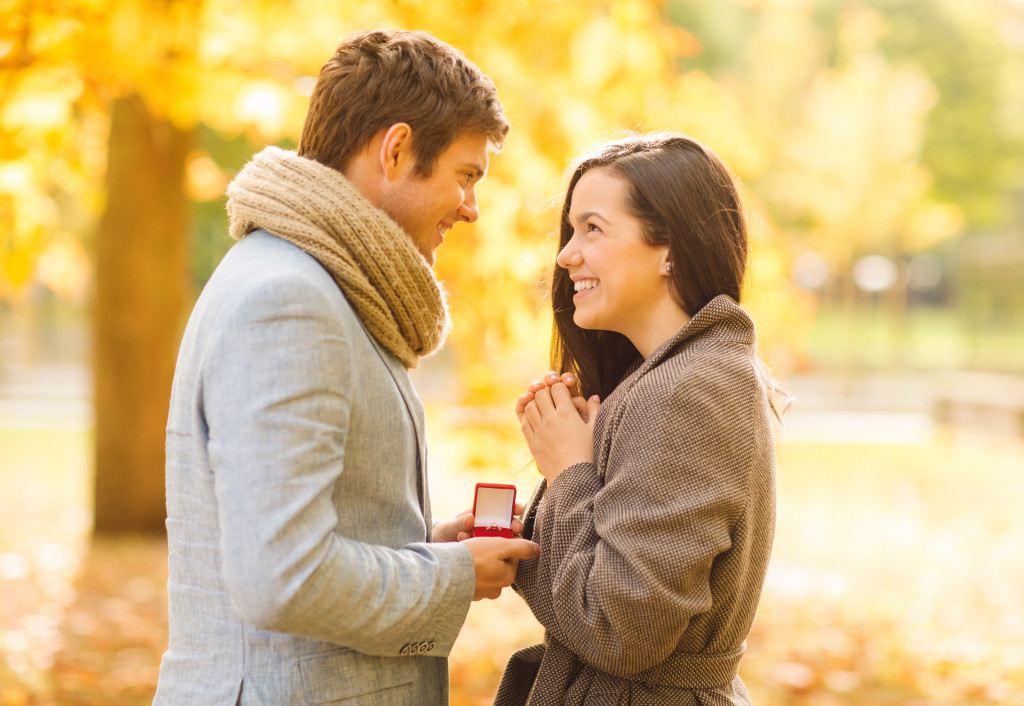 romantic man proposing to a woman in the autumn park