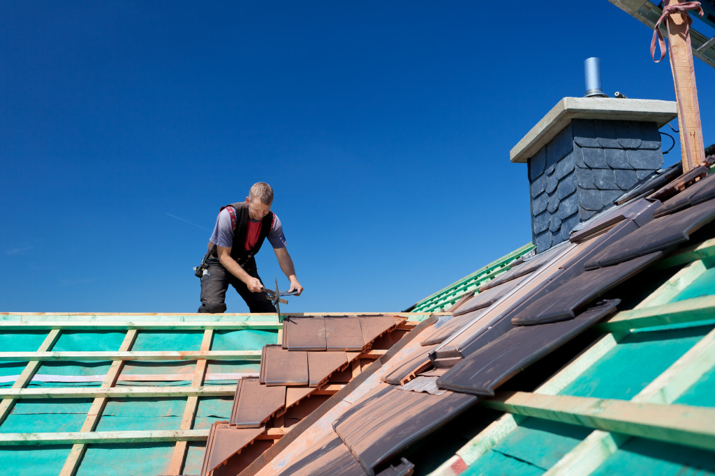 male roof contractor in the roof installing frames and shingles