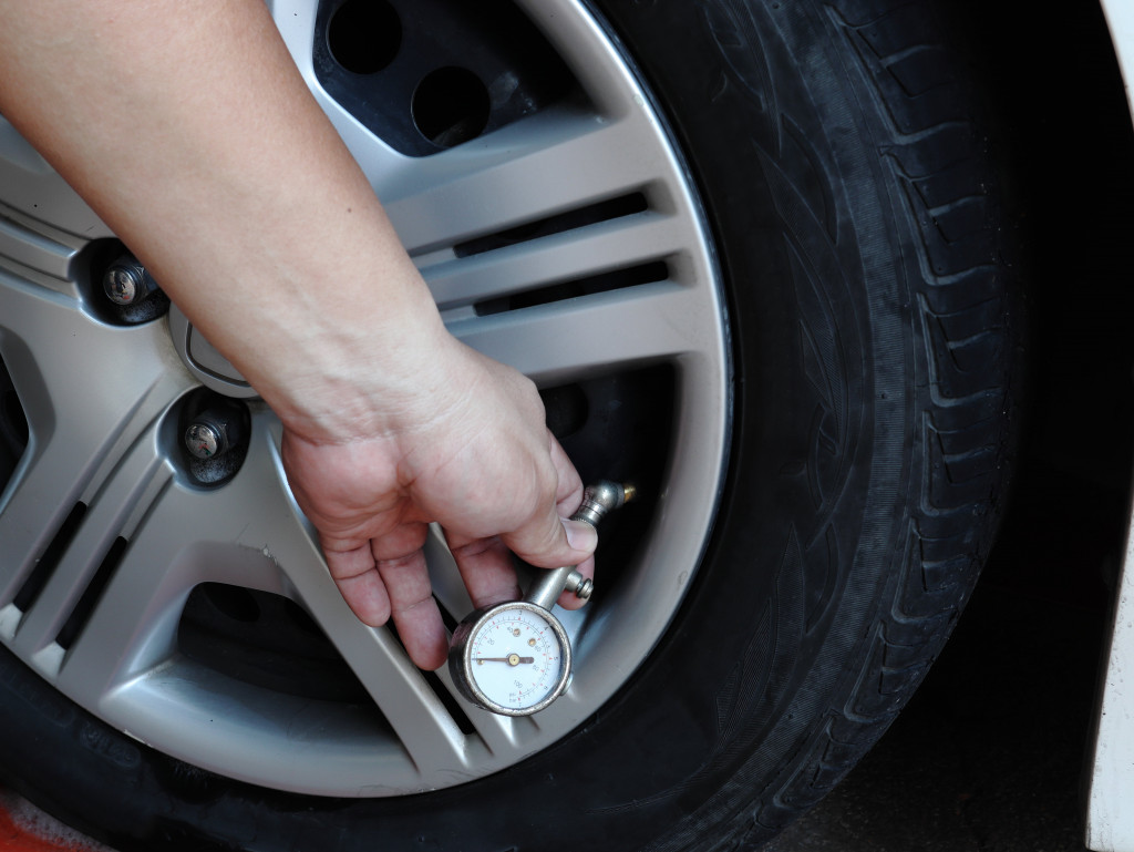 A person using a pressure gauge to check a car tire