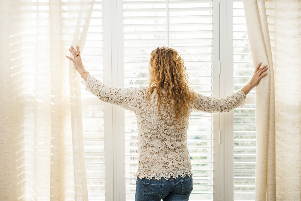 woman on the window opening the curtain