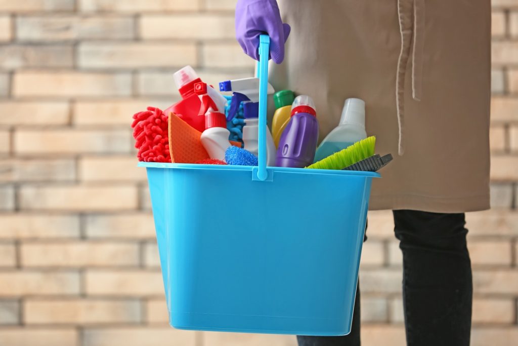 a person holding a basket of home cleaning products