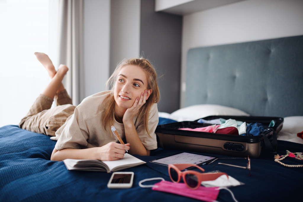 woman thinking and listing down the things she'd bring for travel