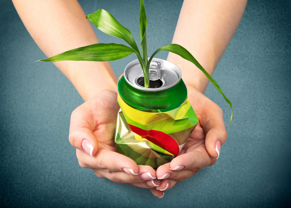 a hand holding a soda can with a plant in it