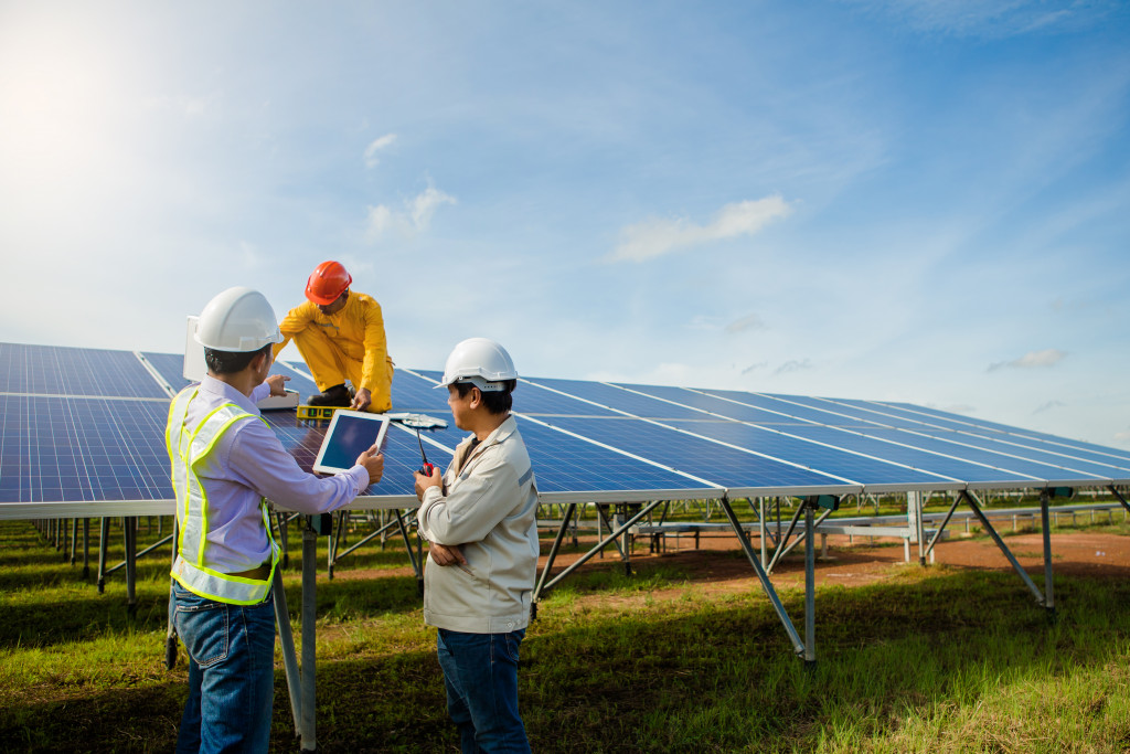 3 workers carefully installing solar panels in an open area